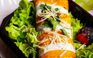 side view of pancake roll with chicken vegetables and cheese on lettuce in a delivery box