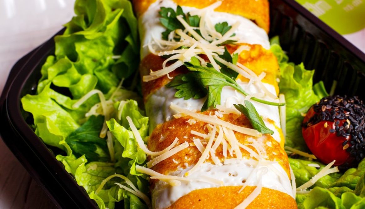 side view of pancake roll with chicken vegetables and cheese on lettuce in a delivery box