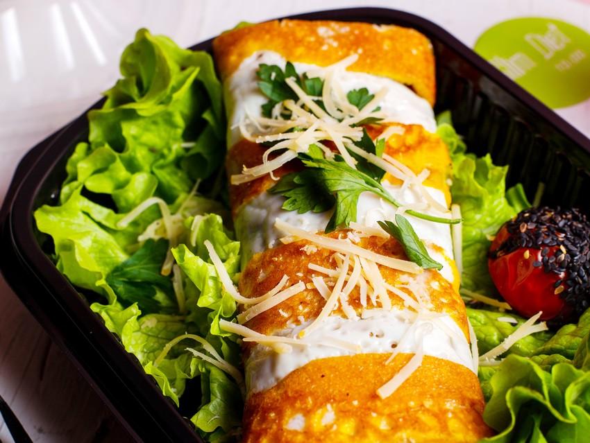 side view of pancake roll with chicken vegetables and cheese on lettuce in a delivery box